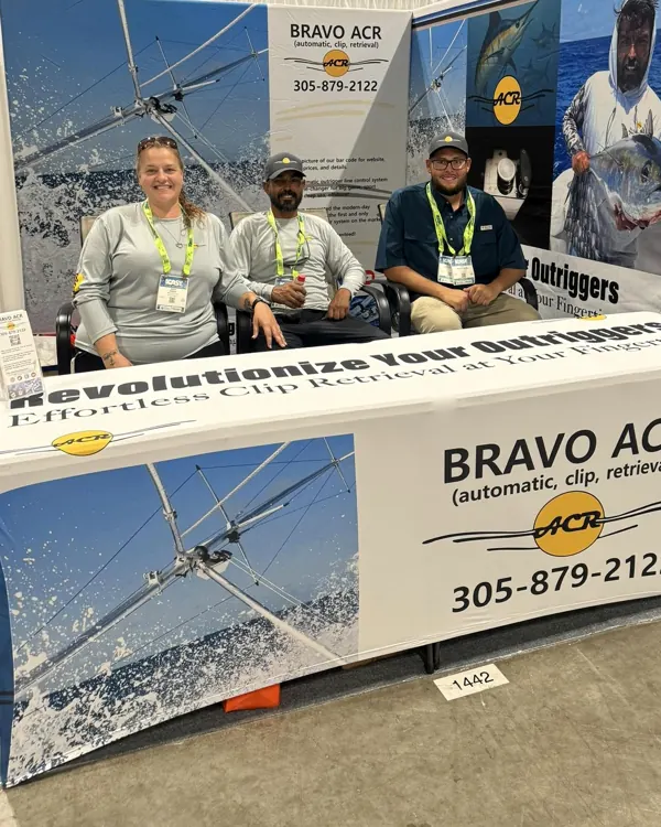 The Bravo ACR booth at ICAST 2025: three people seated behind Revolutionize Your Outriggers and Bravo ACR banners
