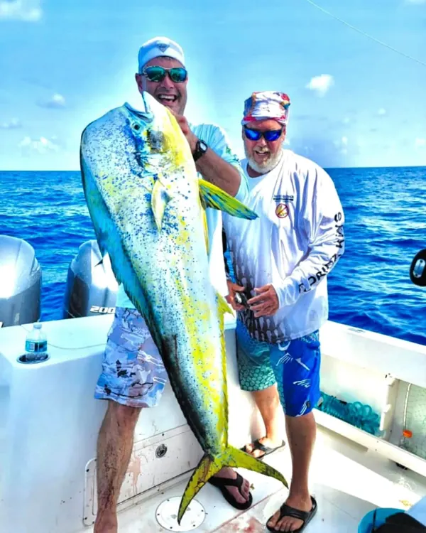 Two anglers with a large mahi on a boat