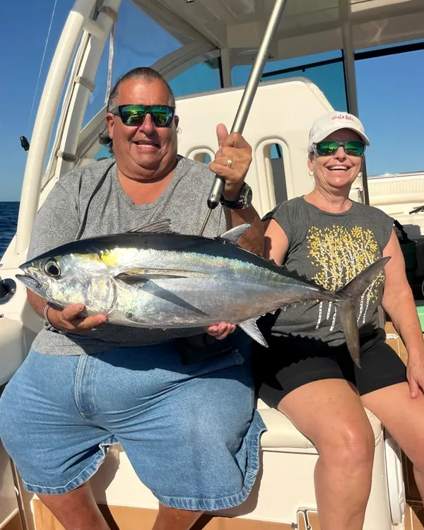 Two people seated in a boat holding a tuna