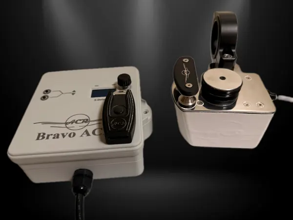 Studio shot: a white Bravo ACR box with a black handheld fob docked on top, beside a white motor and pulley unit with a pole clamp